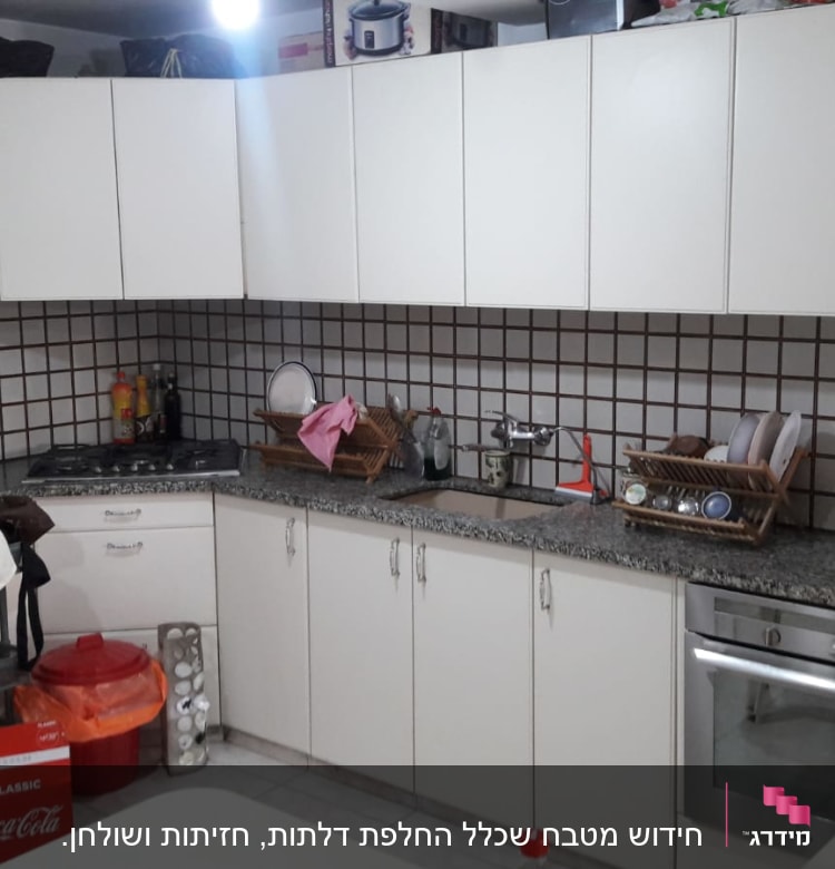 מטבח עם ארונות לבנים, כיור, ותנור אפייה